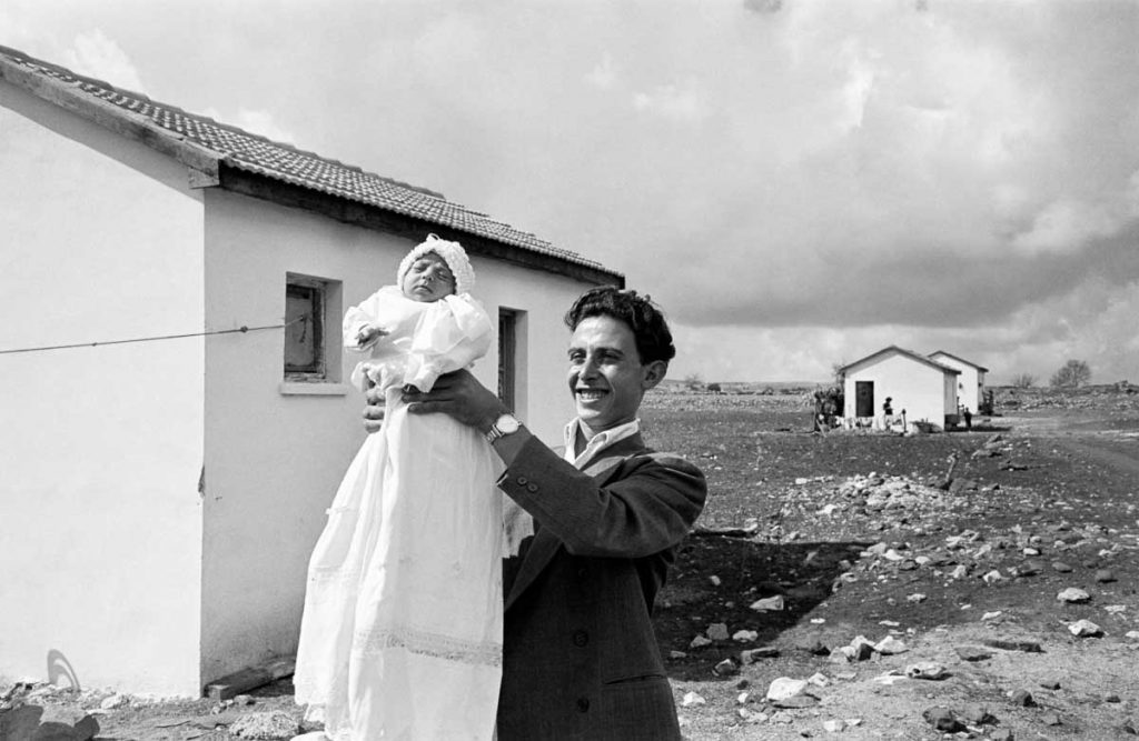 The first child born in the settlement of Alma, in the Upper Galilee. Miriam Trito is held up by her father, Eliezer. 1951.