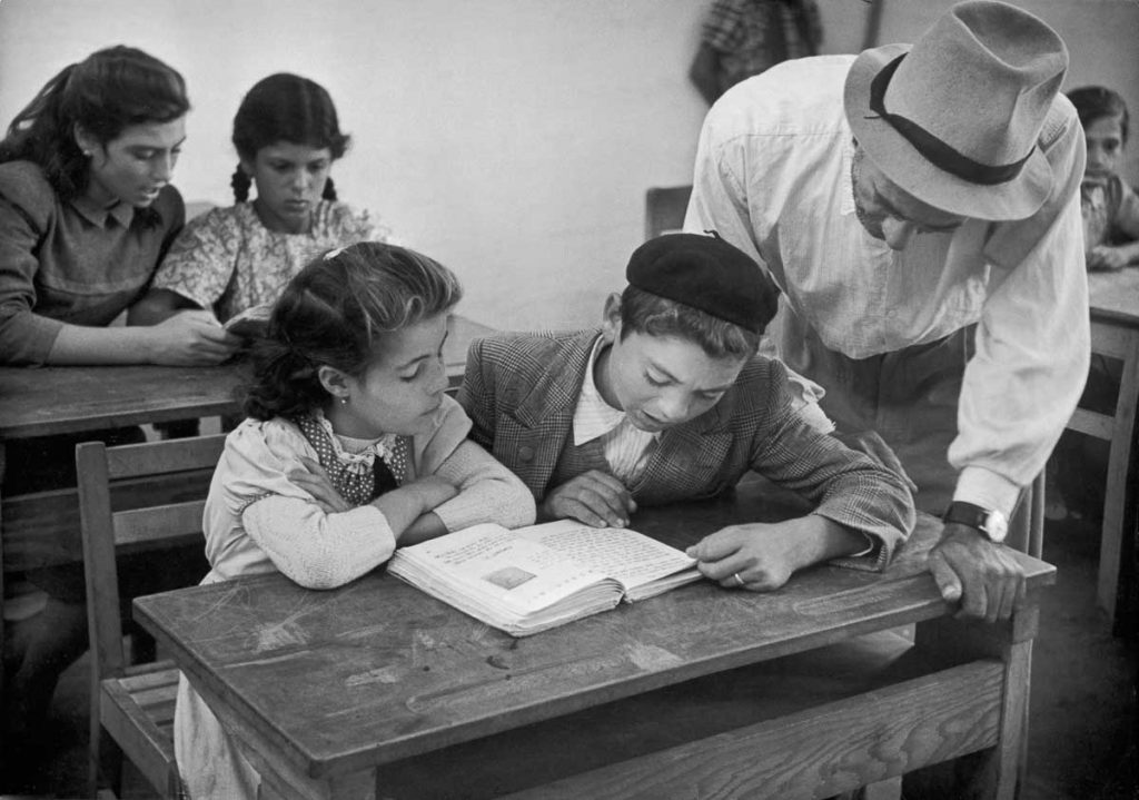 In the village of Alma, schoolchildren learn Hebrew under the supervision of a teacher who is an immigrant from Tripoli. 1951.