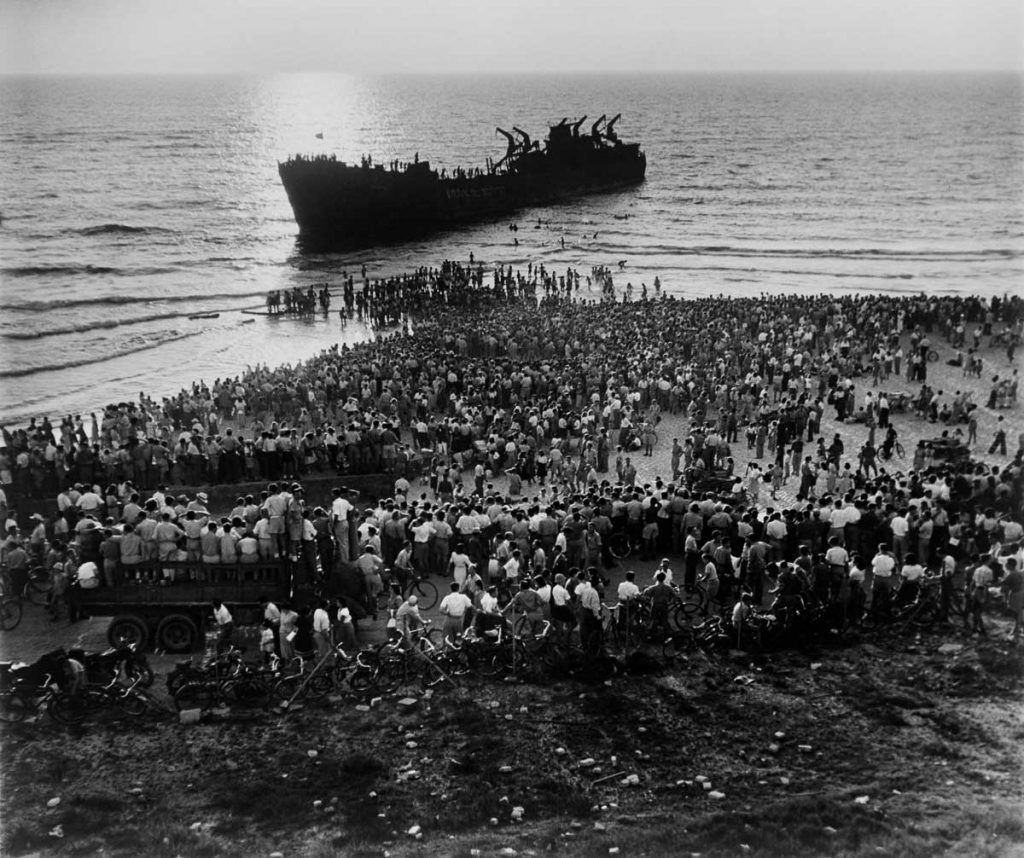 Crowds gather along the Tel Aviv beachfront to look at the wreckage of the Altalena, the ship carrying 500 Jewish immigrants as well as arms. Tel Aviv, June 1948.