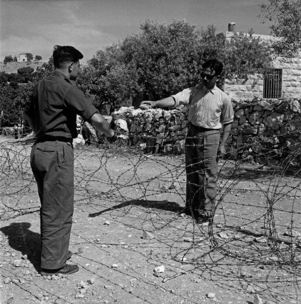 A divided sector of an Arab/Israeli village with a barbed wire border. 1948.